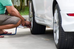 Man checking tire pressure on passenger car